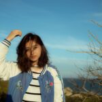 Portrait of a young woman enjoying the outdoors in Đắk Ya, Gia Lai, Vietnam under a clear blue sky.